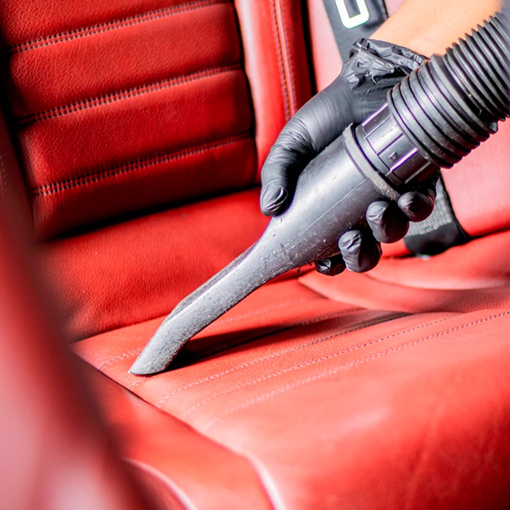 Professional deep interior vacuum extraction on red leather automotive seats at CleanWorx