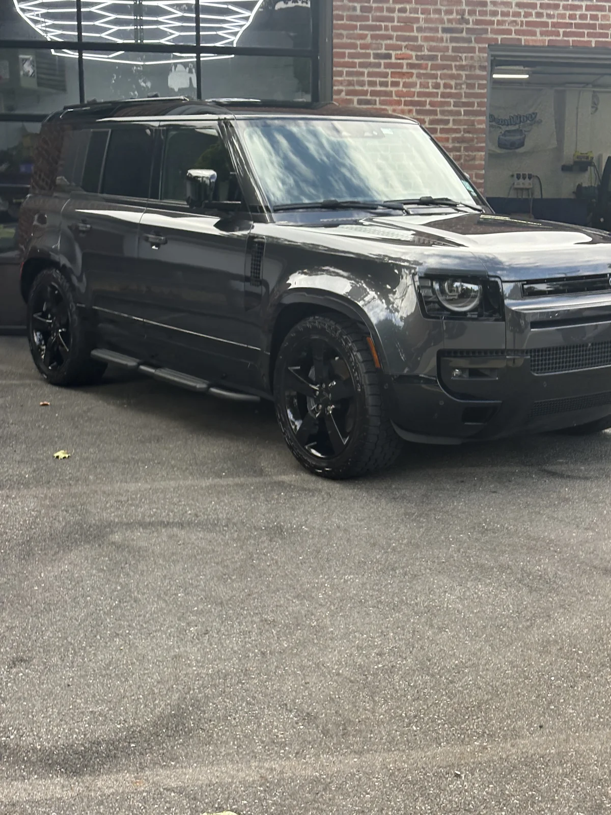 Land Rover Defender 110 outside CleanWorx shop with hex lights visible inside
